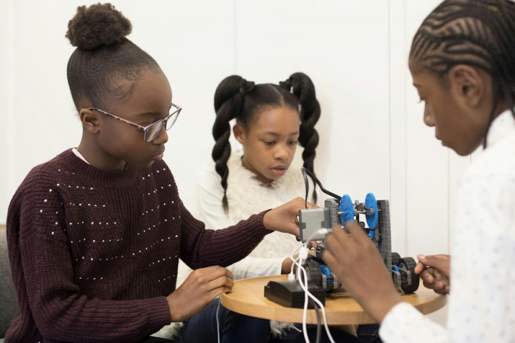 Three students work together to wire and adjust a small robot